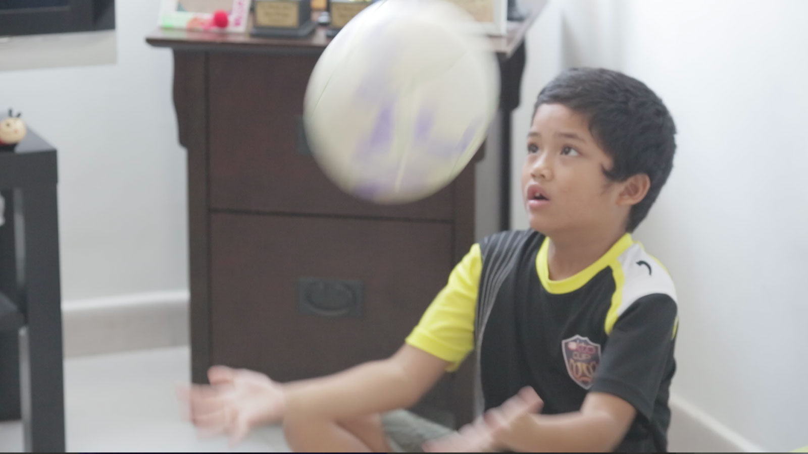 One of Fizah's children juggling a ball in the house